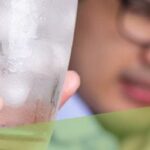 man with sensitive teeth and holding glass of cold water with ice.jpeg